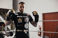 Caucasian male boxer wearing gloves and training in an indoor gym setting.